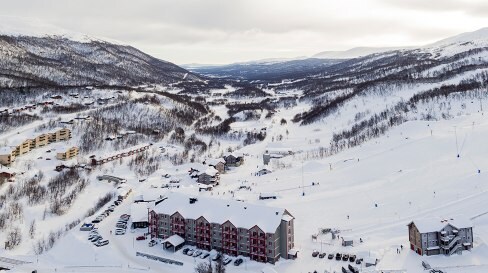 En vuxen och tre barn med skidor i slalombacken i Tänndalen