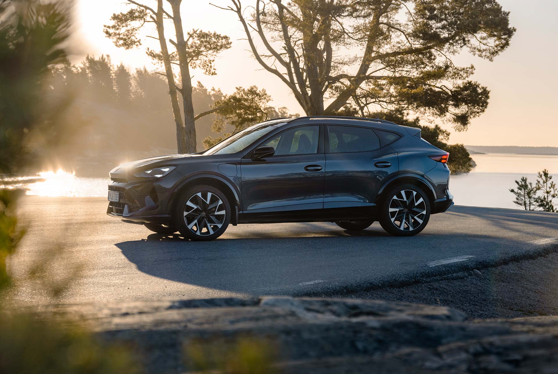 A three quarter front view of the new CUPRA Formentor 2024 car in motion, in the century bronze matt colour, with a blurred background.
