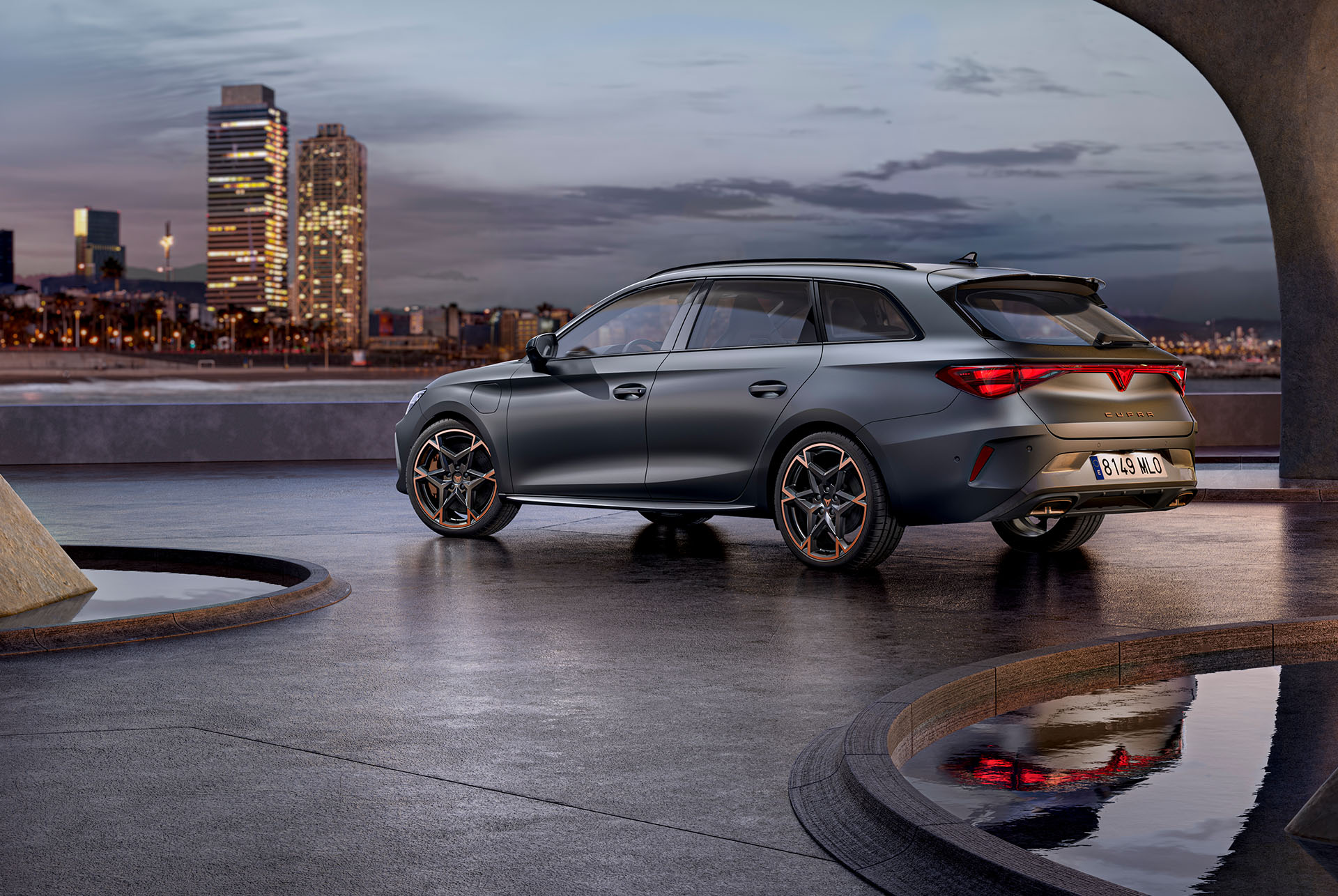 Nya cupra leon sportstourer 2024-teknik parkerad på cement, struktur med glödande kanter, med utsikt över stadens skyline i skymningen. Bilen visas i matt grå lack med kopparfärgade och svarta lättmetallfälgar.