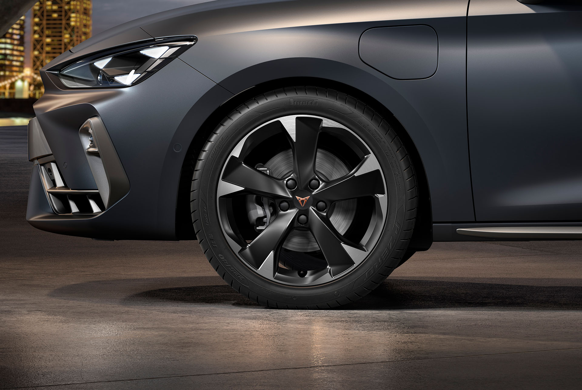 Främre sidovy av den vänstra bearbetade silverfärgade Garbi-lättmetallfälgen på nya cupra leon sportstourer 2024, däck, signaturstrålkastare och grå kaross