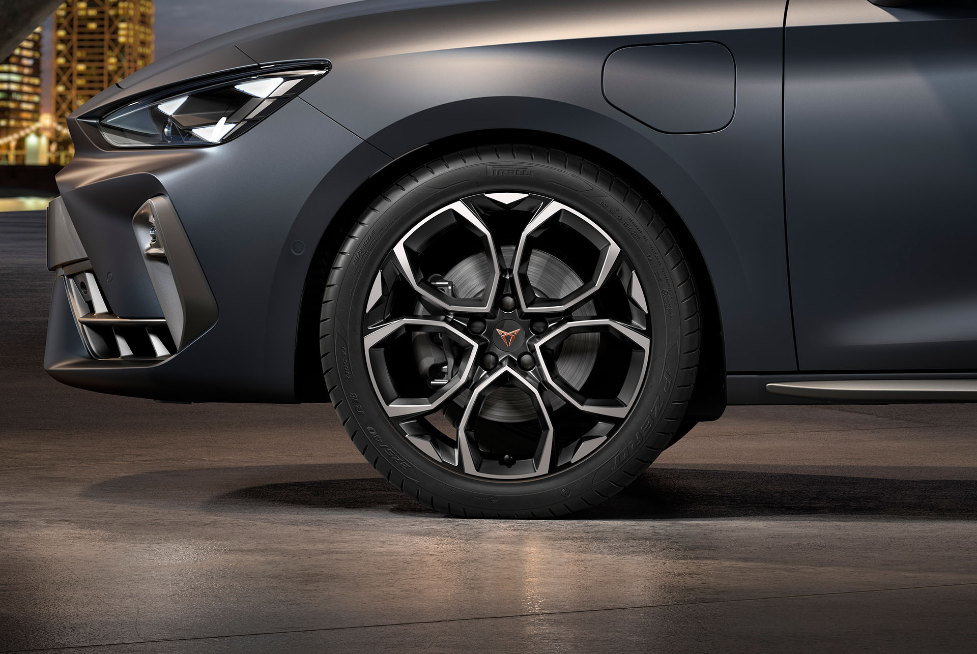 Sidovy framifrån av den vänstra bearbetade lättmetallfälgen i silver och svart Windstorm för nya cupra leon sportstourer 2024, däck, signaturstrålkastare och grå kaross