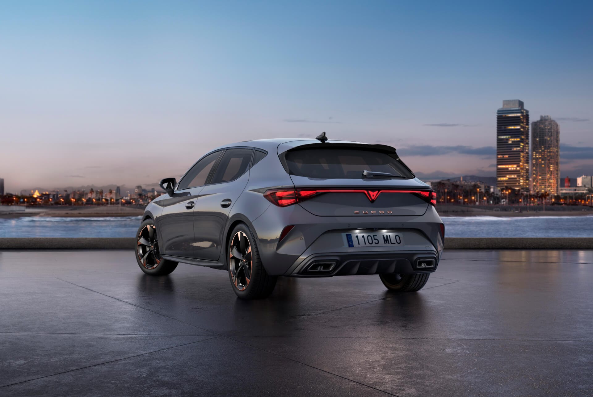 Bild bakifrån av den nya blankgrå bilmodellen cupra leon 2024 med dynamisk chassikontroll samt svarta och kopparfärgade lättmetallfälgar. Stad i bakgrunden vid solnedgång.