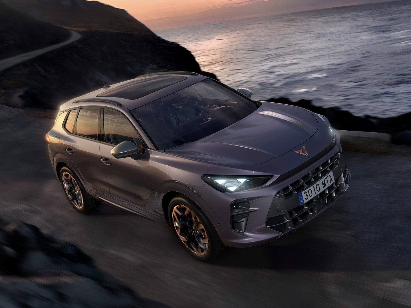 CUPRA Terramar, med Dynamic Chassis Control (DCC), som kör på en väg nära vatten, färgen är Dark Void och 20-tums lättmetallfälgar Hadron Copper. 