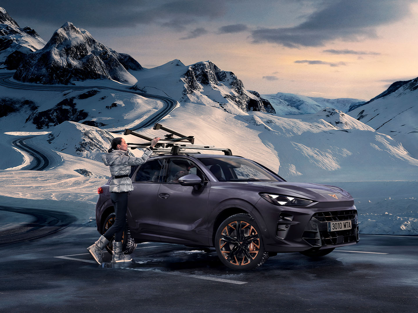 CUPRA Terramar med snöig bakgrund, som visar skidhållare monterade på taket, en av de transportlösningar som erbjuds. En kvinna använder dem för att transportera sina skidor.