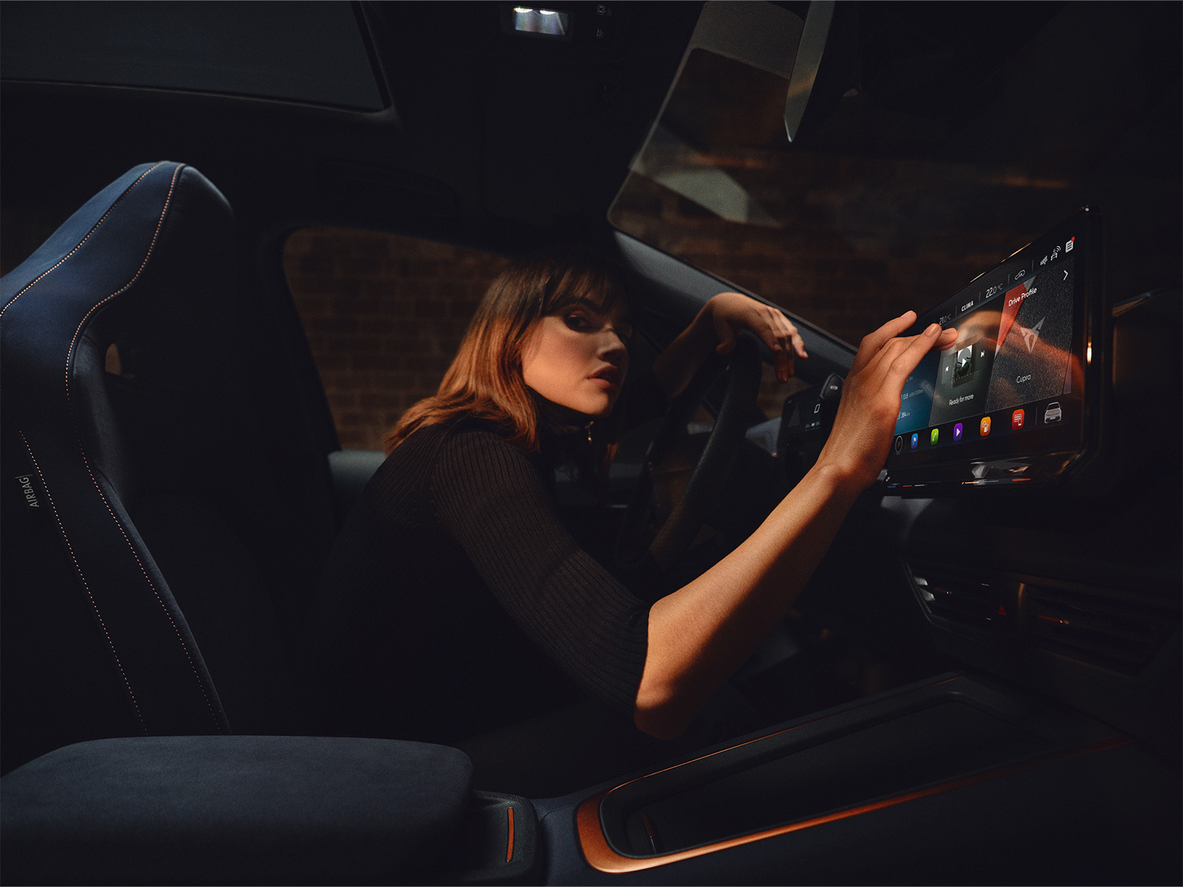 Kvinna som använder bilens infotainmentenhet för att söka efter trådlösa uppdateringar och se till att hon har den senaste CUPRA-programvaran