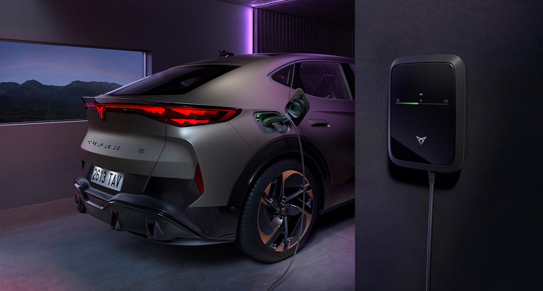 CUPRA Tavascan VZ i bronsfärgad laddningsbil med CUPRA Charger, parkerad i ett modernt garage med lila stämningsbelysning.